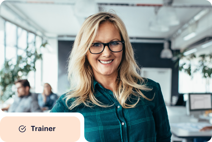 Woman in an office smiling with a circled checkmark next to the word trainer