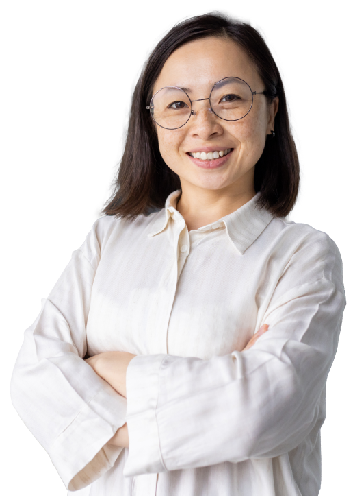 A person in a white blouse and glasses smiles and poses for the camera with arms crossed