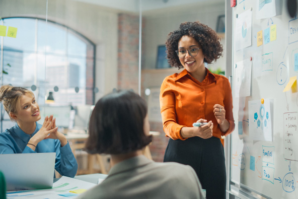 Colleagues meet and collaborate in front of a white board